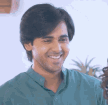a man in a green shirt is smiling and looking at something