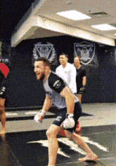 a man wearing boxing gloves is running on a mat in a gym ..
