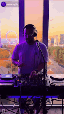 a man wearing headphones is playing a dj set in front of a window