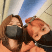 two women wearing face masks and sunglasses pose for a picture