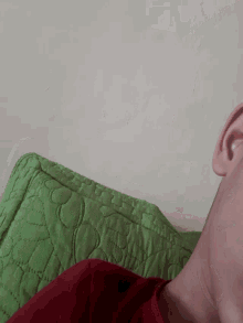 a close up of a person 's ear with a green quilt in the background