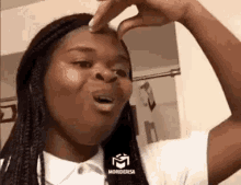 a woman is making a funny face while holding her finger to her forehead .