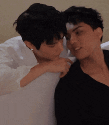 a man in a black shirt is kissing another man on the neck