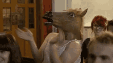 a woman wearing a horse head mask is dancing in front of a group of people .