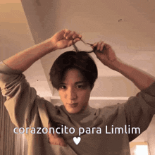 a young man is holding his hair in a ponytail with the words " corazoncito para limlim " written above him