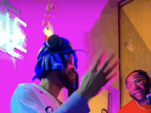 a man wearing headphones and a blue hat is standing in front of a pink wall .