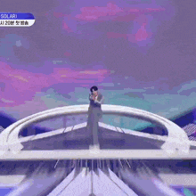 a man in a suit is standing on a stage in front of a purple sky .