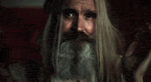 a man with long hair and a beard is making a funny face .