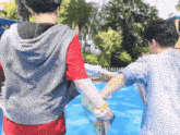 two men are holding hands in front of a swimming pool