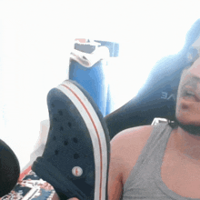a man wearing a gray tank top and a pair of crocs