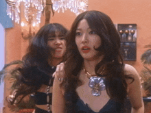 two women are standing next to each other with one wearing a necklace