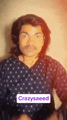 a man with long hair and a mustache is wearing a polka dot shirt and says crazysaeed