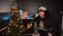 a man is standing in front of a microphone in front of a christmas tree