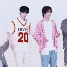 a group of young men are standing next to each other . one of the men is wearing a phyps jersey .