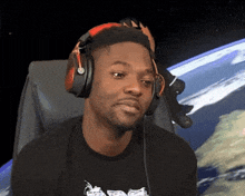 a man wearing headphones is sitting in front of a screen that shows the earth