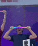 a man wearing sunglasses is holding a rainbow colored light up stick over his head