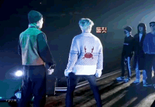a man wearing a sweater with a crab on it stands in front of a group of people
