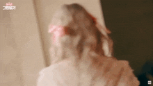 a woman with a red bow in her hair is standing in front of a door .
