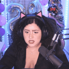 a woman wearing headphones and a cat ear headband looks at the camera