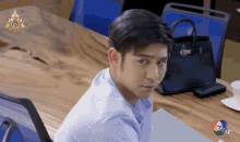a man sitting at a table with a purse on it and the number 7 in the corner