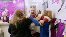 a man is being held by two women in a room .