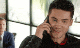 a man is talking on a cell phone and smiling .