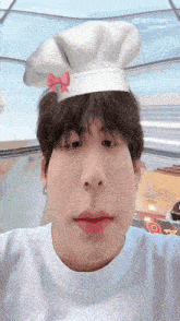 a young man wearing a chef hat with a red bow on it