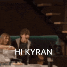 a blurred image of a person sitting at a table with the words hi kyra on the bottom