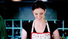 a woman wearing an apron is smiling and cooking in a kitchen