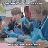 two men wearing blue aprons and gloves are preparing food with a caption that says belum bisa ngasih kabar