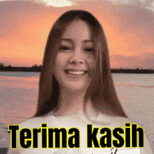 a woman is smiling in front of a sunset and the words terima kasih are on the bottom