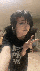 a girl wearing a black shirt that says ' ncpr ' on it is giving a peace sign