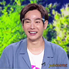 a man wearing a blue jacket and a white shirt is smiling while wearing glasses ..