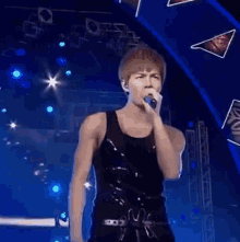 a man in a black tank top is dancing on a stage with blue lights behind him .