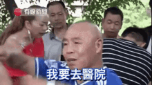 a group of people are standing around a bald man with chinese writing on his face .