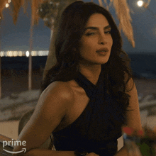a woman in a blue dress is sitting at a table with an amazon prime logo on her arm
