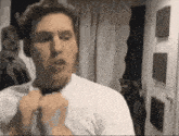 a man in a white shirt is tying a tie