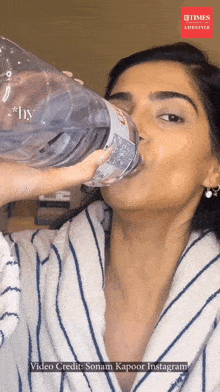 a woman drinking water from a bottle that says ' hy ' on it