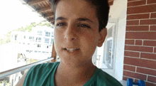 a young boy in a green shirt is standing on a balcony