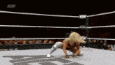 a female wrestler is kneeling down in a wrestling ring while a crowd watches .