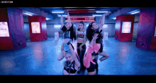 a group of young women are dancing in front of a sign that says secret entrance