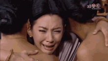 a woman is crying while being hugged by two other women and the number 33 is on the screen