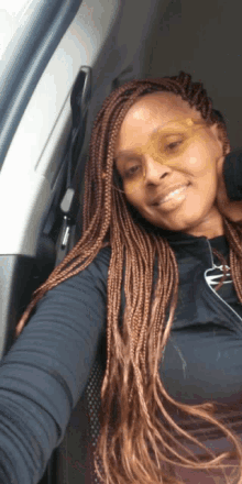 a woman wearing braids and sunglasses is smiling for the camera