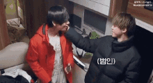 two men are standing next to each other in a room and one of them is petting the other 's face .