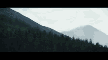 a mountain with trees on the side of it and a cloudy sky