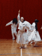 a group of women in white dresses are dancing on a wooden floor