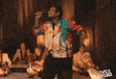 a man in a colorful jacket is dancing in front of a group of people playing instruments .