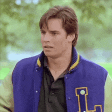 a man wearing a blue and yellow varsity jacket with the letter l on it .
