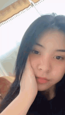 a close up of a young woman 's face with her hand on her face .