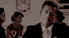 a man in a suit and tie is holding a glass of wine while sitting at a table .